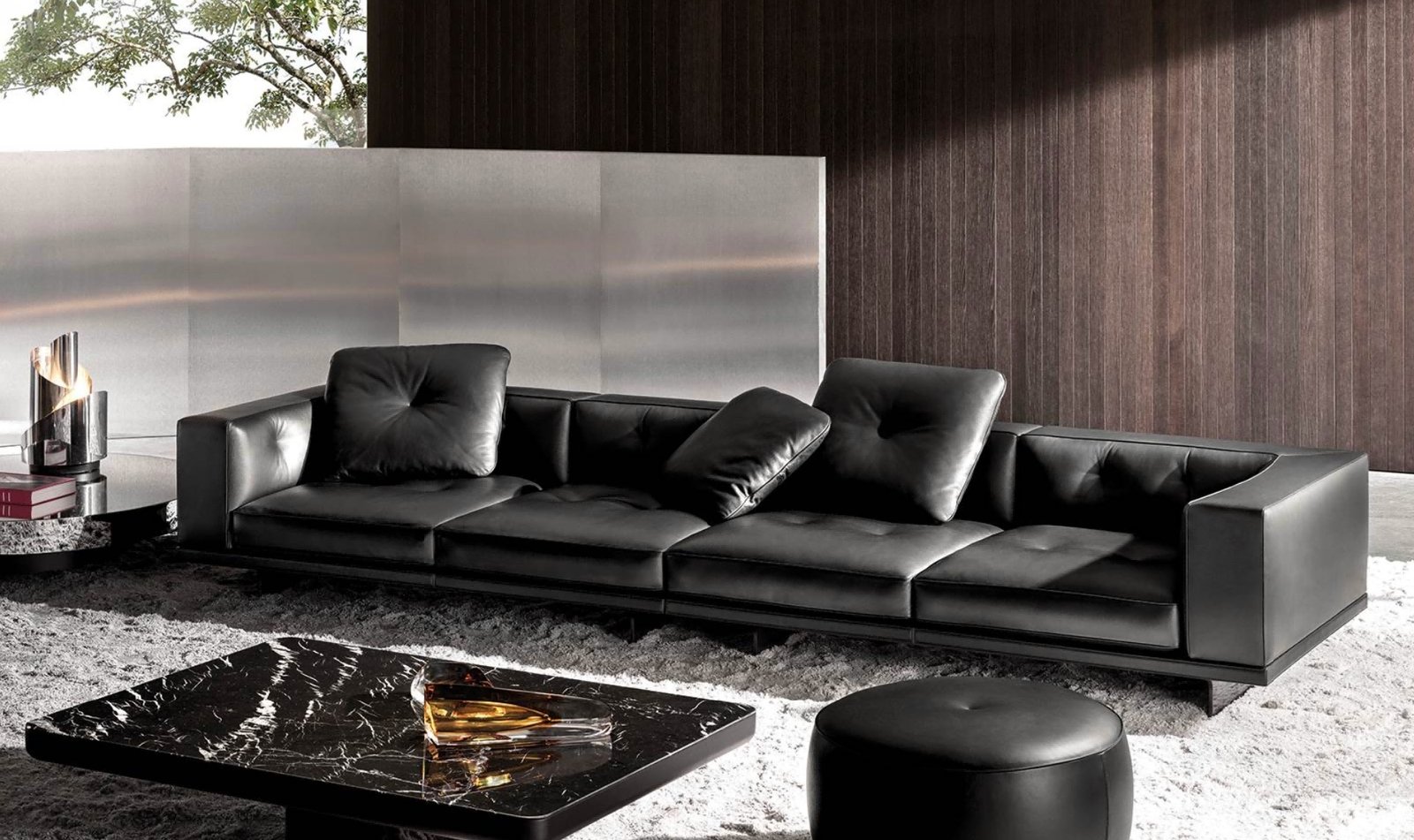 Long black smooth upholstered sofa with low arms and loose dark cushions