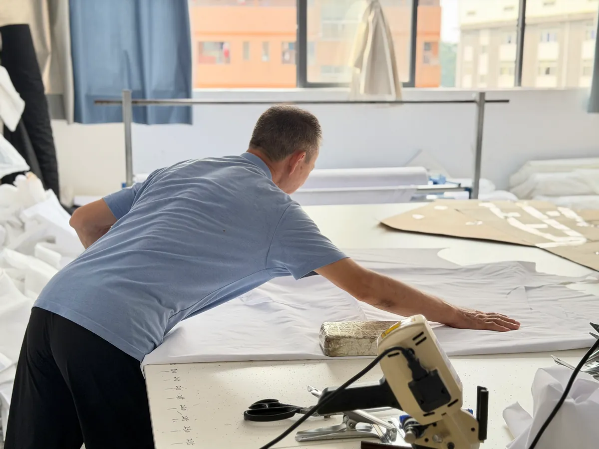 Fabric laid out across a workshop cutting table