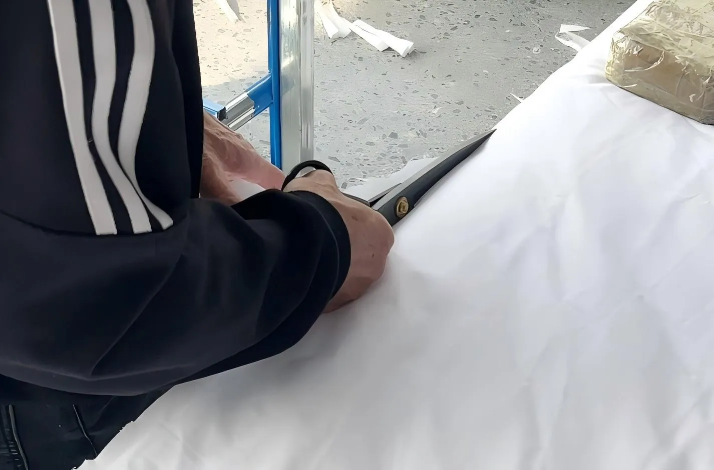 Hands working on a light-coloured upholstered surface during furniture production