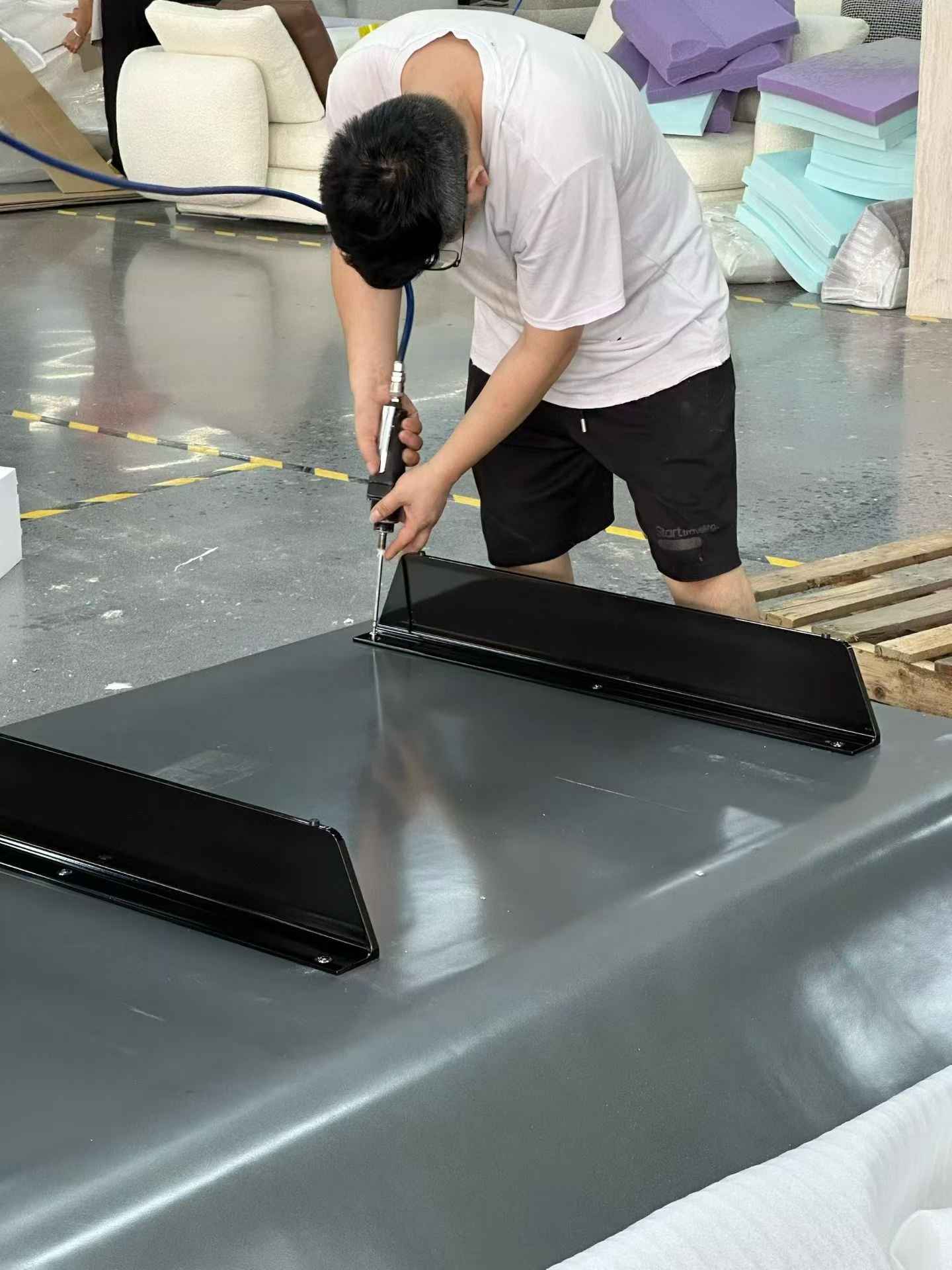 Worker fastening the underside of an upholstered furniture component