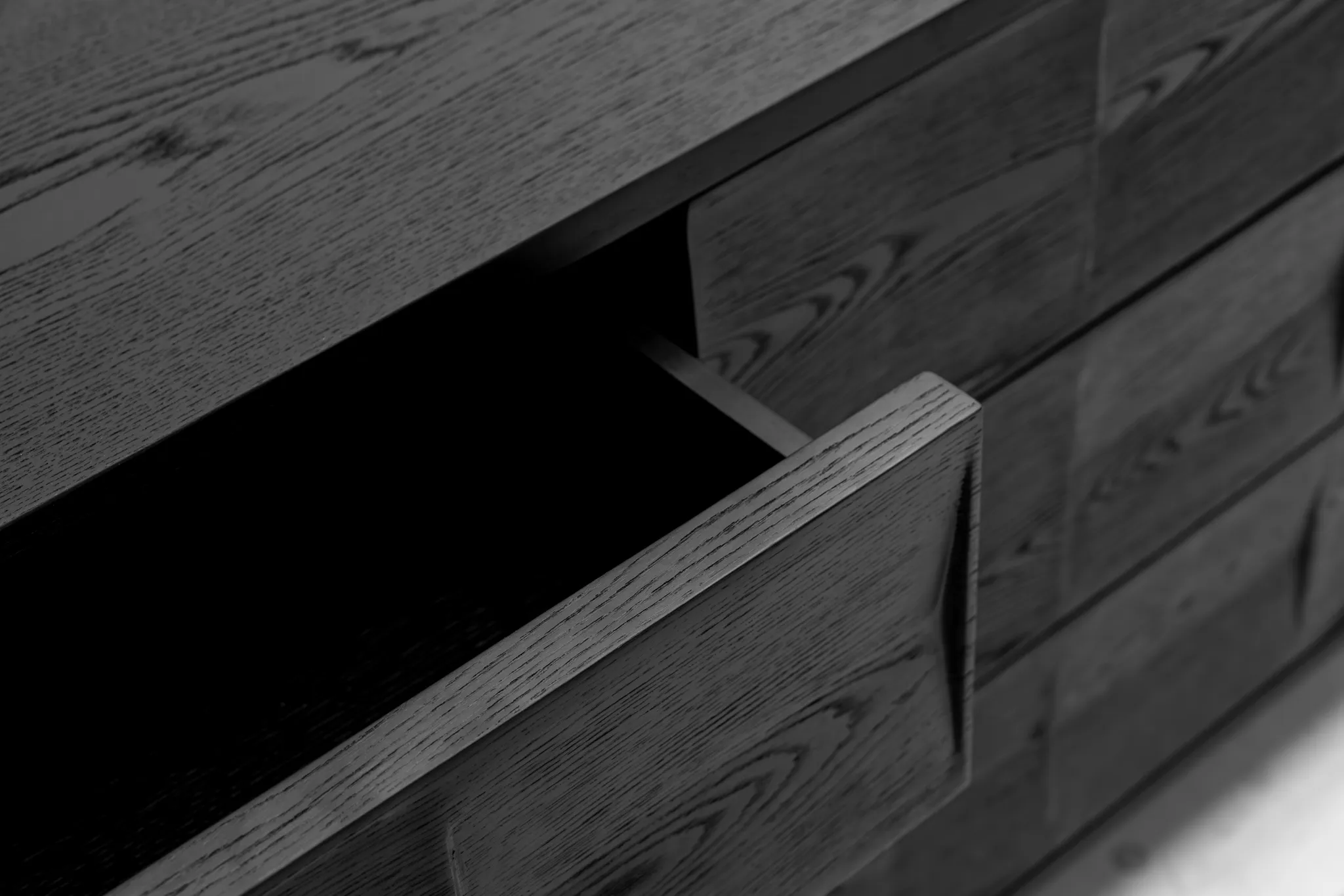 Close detail of dark wood-grain cabinet fronts with a partly open drawer