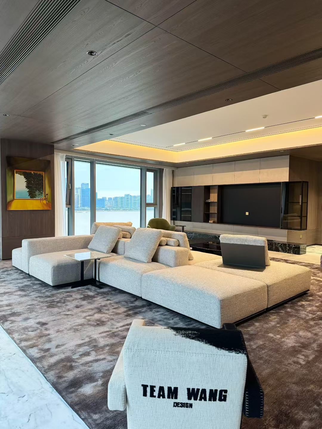 Pale modular seating arranged within a broad open room beside large windows