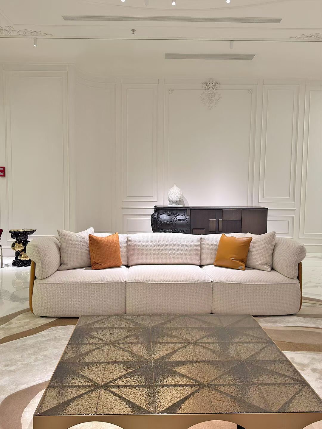 Straight pale sofa centred on a wall with open floor and a rug in front