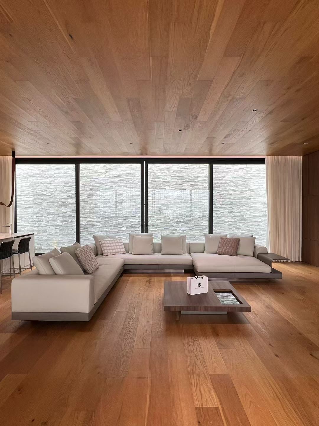 Living space combining wood-toned wall and ceiling surfaces with pale upholstered seating
