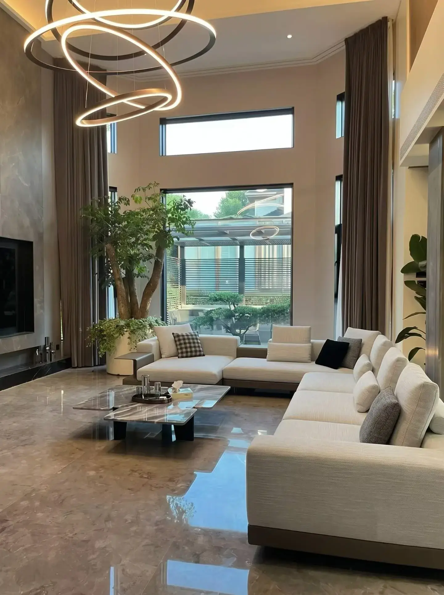 Double-height living space with sofa seating, large glazing and a route beside the furniture